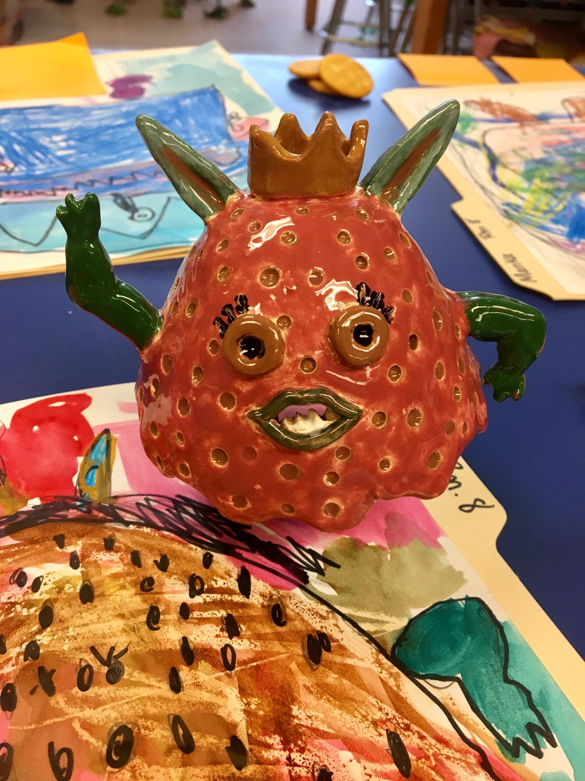 Student artwork of clay sculpture of strawberry character.